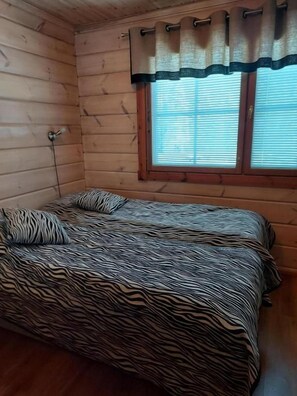 A room with a bed, a window with blinds, and a curtain.