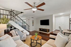 A modern living room with a ceiling fan, a staircase, a flat-screen TV, and a dining area. - 3BR Scottsdale Retreat, Pool, Near Old Town (Scottsdale)
