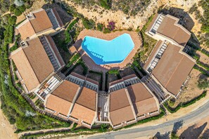 An aerial view of a resort with a central swimming pool surrounded by multiple buildings with terracotta roofs. - La Roccia Vermentino Costa Paradiso, Sardinia (Costa Paradiso)