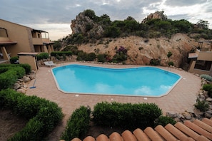 A rectangular swimming pool with a tiled deck, surrounded by greenery and a rocky hillside. - La Roccia Vermentino Costa Paradiso, Sardinia (Costa Paradiso)