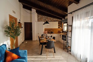 A dining area with a wooden table set for four, a blue sofa with orange cushions, and a potted plant. - La Roccia Vermentino Costa Paradiso, Sardinia (Costa Paradiso)