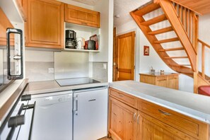 Eine kleine Küche mit Holzschränken, einem eingebauten Geschirrspüler und einer Arbeitsplatte.