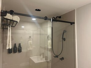 A modern bathroom with a glass shower enclosure, a towel rack with towels, and toiletries. - A Cozy, Stylish Stay in the Heart of Bogotá (Bogotá)