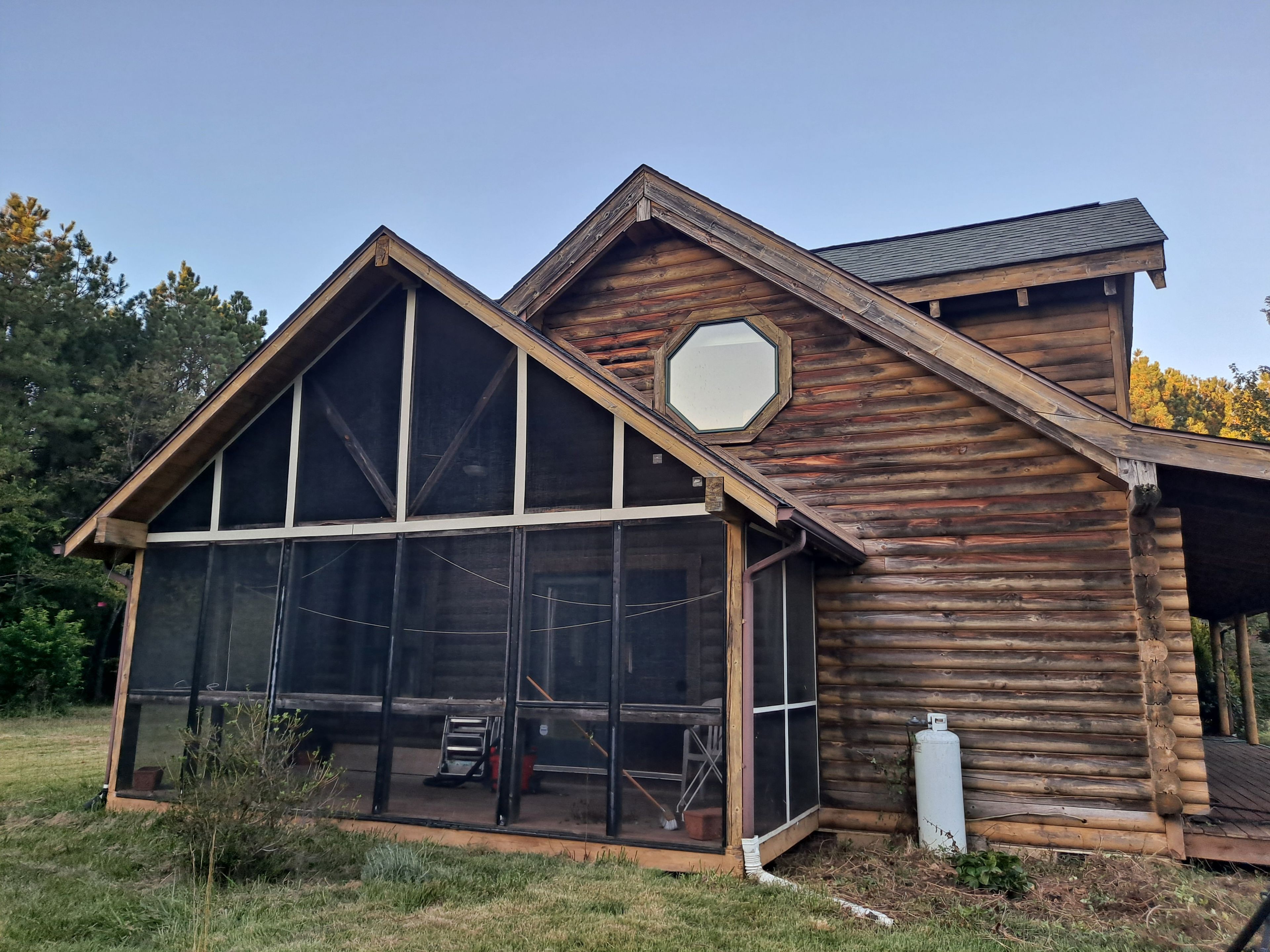 A log cabin with a large glass window, a hexagonal skylight, and a wooden deck.
