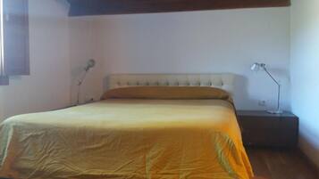 Un dormitorio con una cama, dos lámparas de noche, una mesita de noche y techo de madera.