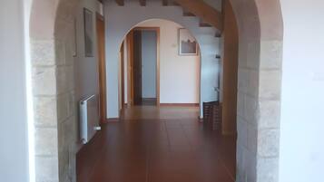 A hallway with an arched ceiling and tiled floor, leading to a door at the end.