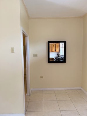 A room with a tiled floor, a door leading to another room, and a framed picture on the wall. - Spacious and centrally located 1 bedroom apartment in the heart of Kingston (Kingston)