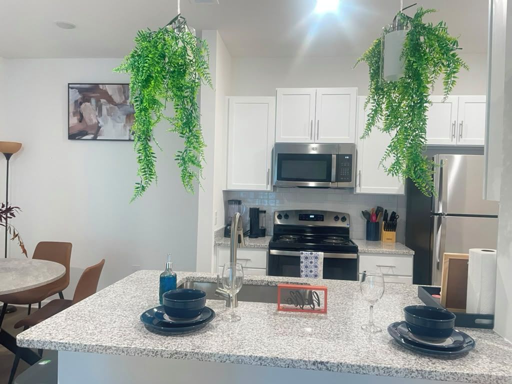 A modern kitchen with white cabinets, a stainless steel microwave, and a black stove.