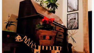 A room with a sofa, a small table, a decorative plant, and framed pictures on the wall.