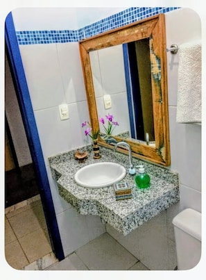 Un bagno con un piano in granito, un lavabo bianco, uno specchio e un porta asciugamani.