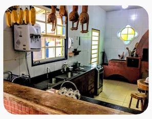 A kitchen with a water dispenser, a sink, and hanging utensils.