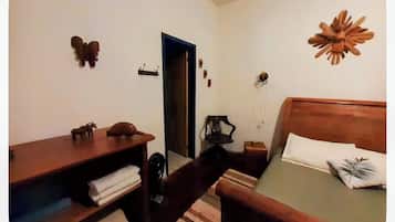 A bedroom with a bed, a desk, a chair, and a small table.