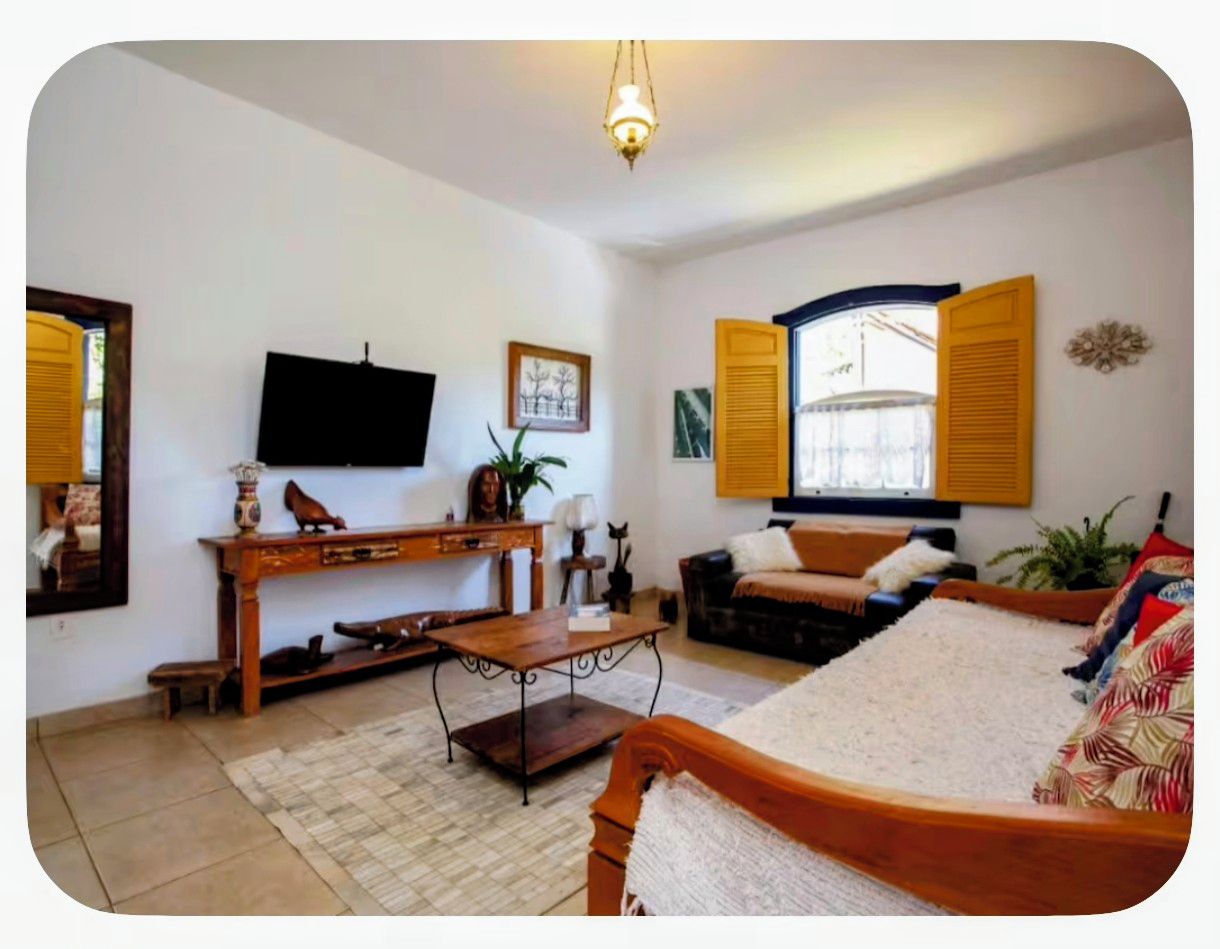 A living room with a television, sofa, coffee table, and a wooden bench.