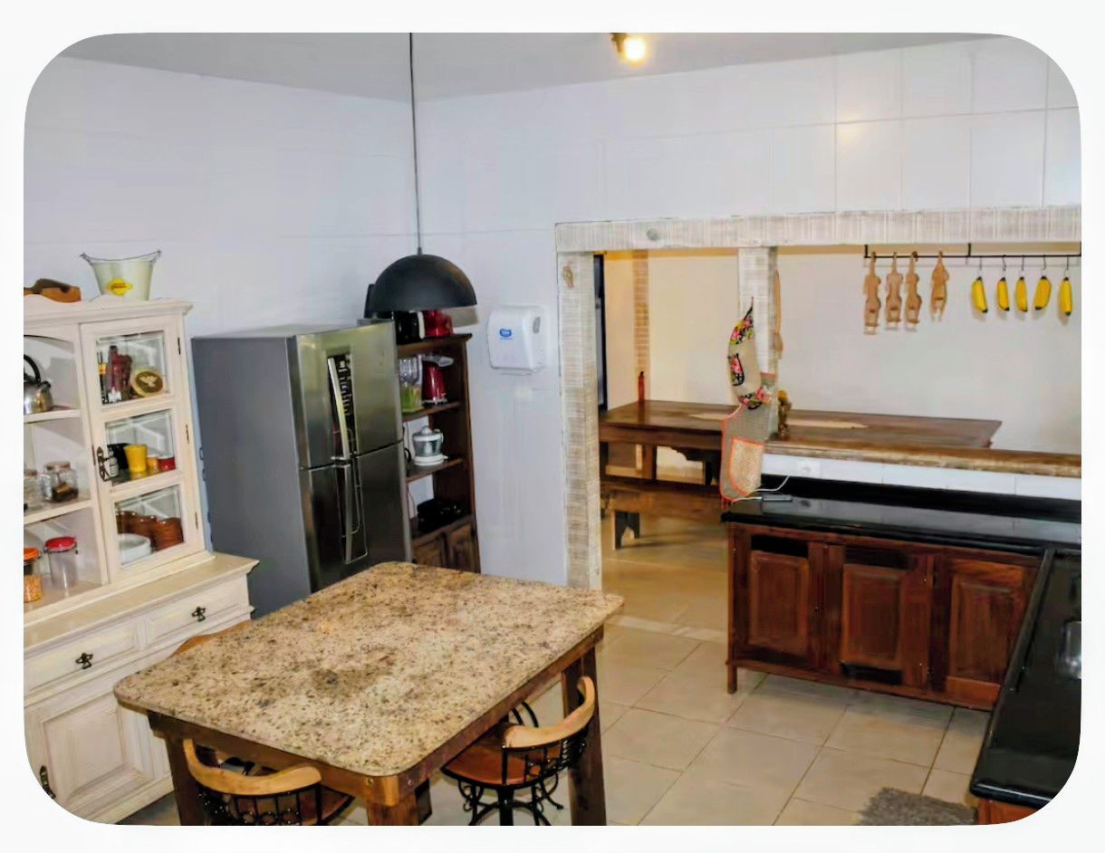 A kitchen with a granite countertop, wooden cabinets, a refrigerator, and a dining area with a bench.