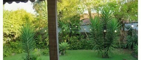 A covered outdoor area with a grassy lawn, palm trees, and a stone pillar.