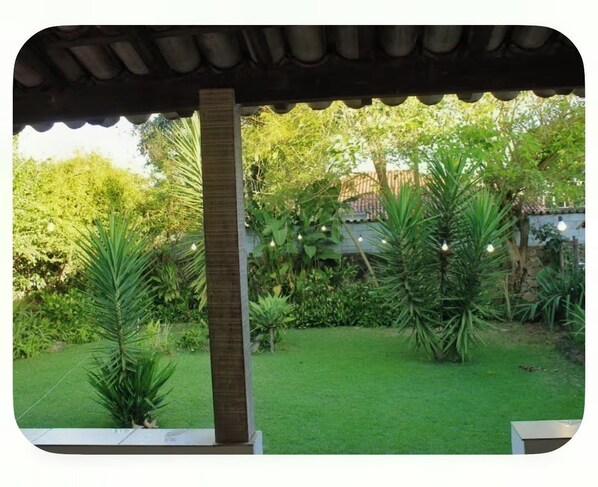 A covered outdoor area with a grassy lawn, palm trees, and a stone pillar.