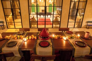 A dining table set for a meal with a central decorative bottle, surrounded by plates, cutlery, and candles. - Villa Jnane Réhann (Marrakech)