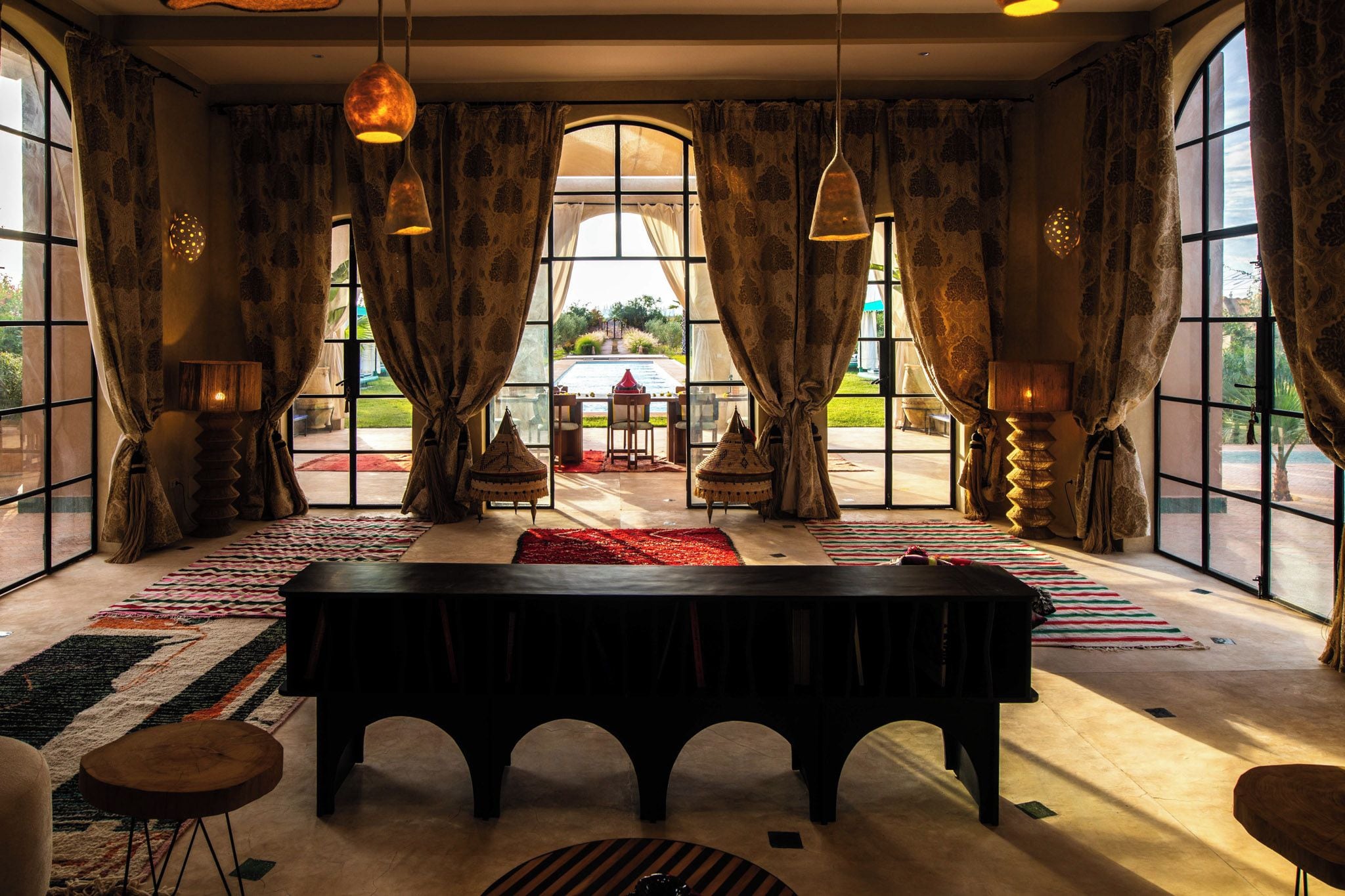 A spacious room with a large table, multiple chairs, and a view of an outdoor area through large windows.