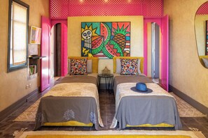 A hotel room with two beds, a colorful mural, and a small table with a lamp. - Villa Jnane Réhann (Marrakech)