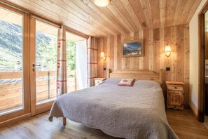 Une pièce en bois avec un lit, une table de chevet, une lampe et un tableau accroché au mur.