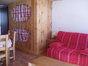 Ein Zimmer mit einer Holzwand, einem roten Sofa, einem Holzstuhl und einem kleinen Tisch.