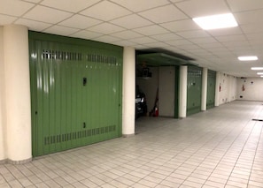 A corridor with green lockers, white tiled flooring, and a ceiling with fluorescent lights. - PALAZZO PRINCIPE - In the heart of STRESA! (Stresa)
