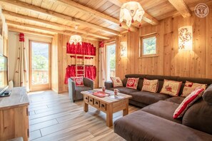 Ein gemütliches Holzinterieur mit einer Couch, einem Sessel und einem Tisch mit einer Tasse.