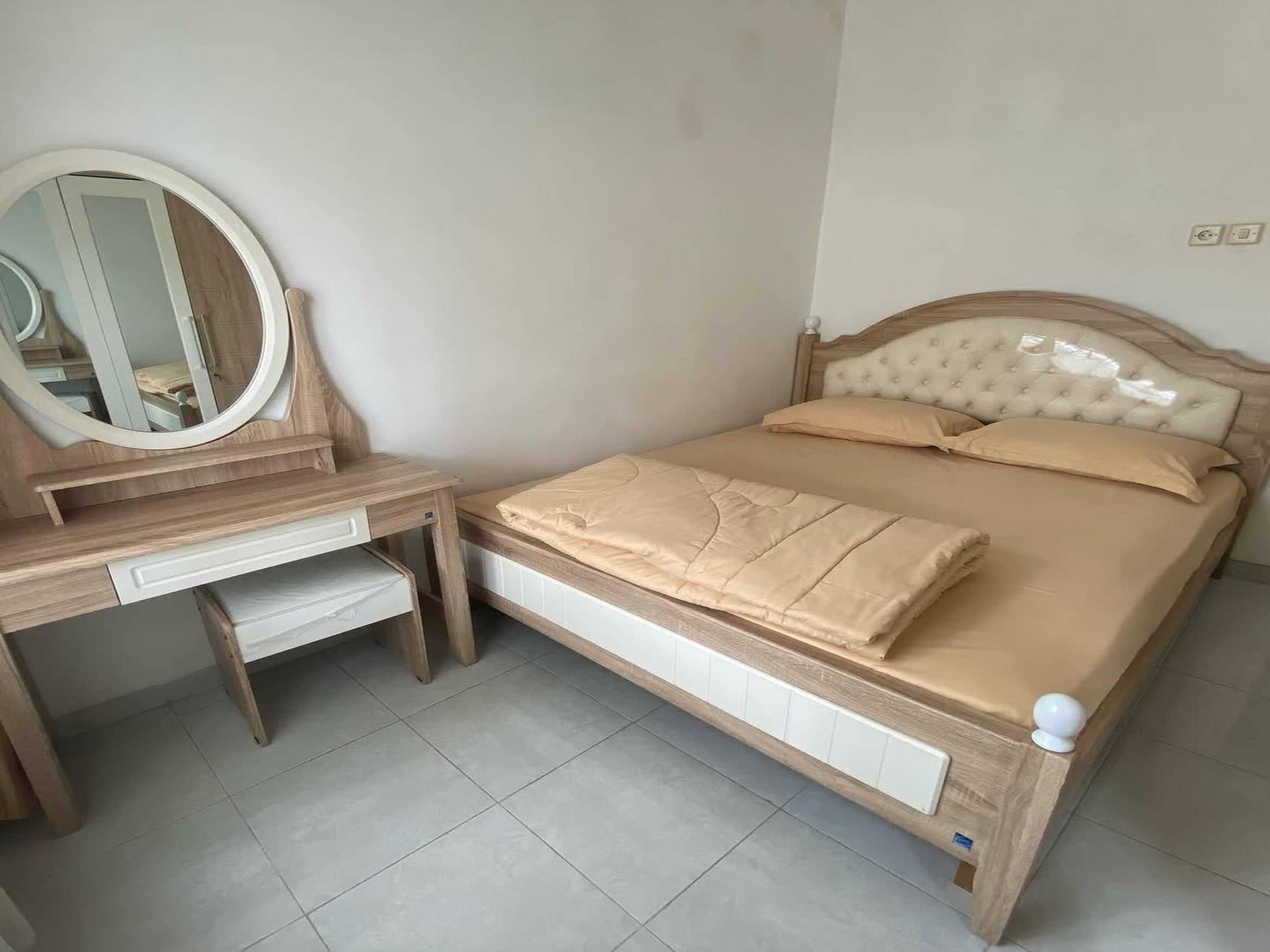 A bedroom with a wooden bed, a bedside table, a mirror, and a radiator.