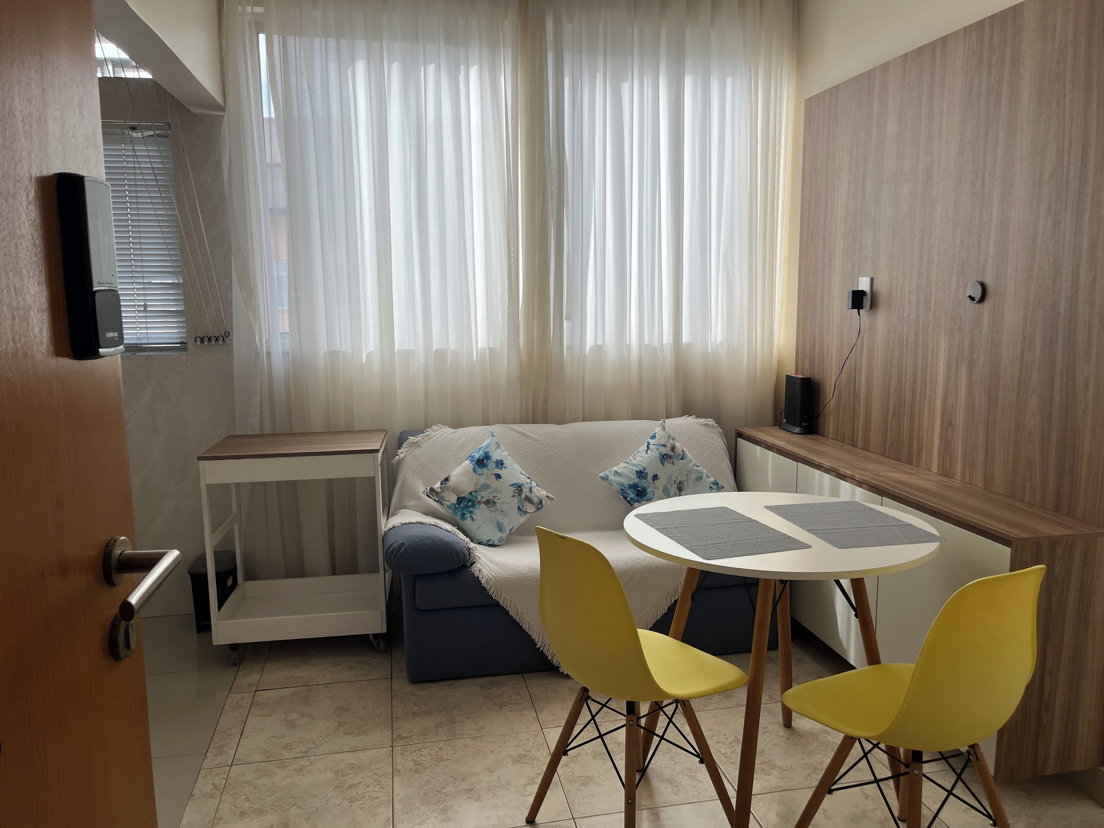 Un espacio habitable moderno con un sofá, una mesita y dos sillas amarillas.