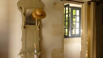 Una habitación con un espejo, un sombrero y una ventana con cortinas.