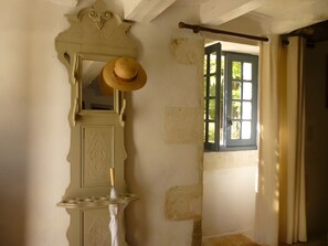 A room with a mirror, a hat, and a window with curtains.