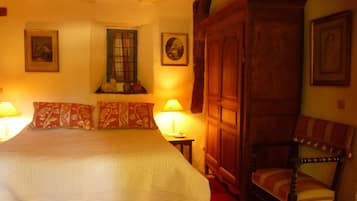 A bedroom with a large bed, a wooden wardrobe, a chair, and two bedside lamps.
