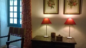 A room with a chair, a table with two lamps, and two framed floral pictures on the wall. - Country House 'Hameau des Rabauds - La Tourderie' with Pool, Private Garden & Wi-Fi (Saint-Pierre-de-Maillé)