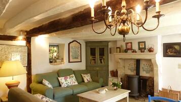 A cozy living room with a green sofa, a wooden table, and a chandelier.