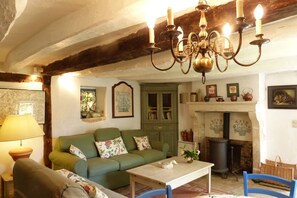 A cozy living room with a green sofa, a wooden table, and a chandelier.