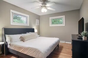 A bedroom with a bed, a ceiling fan, a nightstand, and a dresser. - ⛱3 min→Beach Game Room Hot tub, Firepit, 5min✈ (Traverse City)