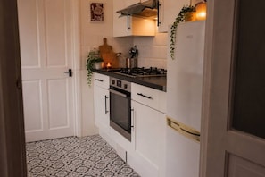 Eine Küche mit weißen Schränken, einem Gasherd, einem Backofen und einem Kühlschrank.