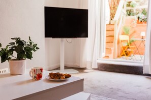 Ein Zimmer mit Fernseher auf einem Schrank, einer Zimmerpflanze, einer Tasse und einem Teller mit Essen.