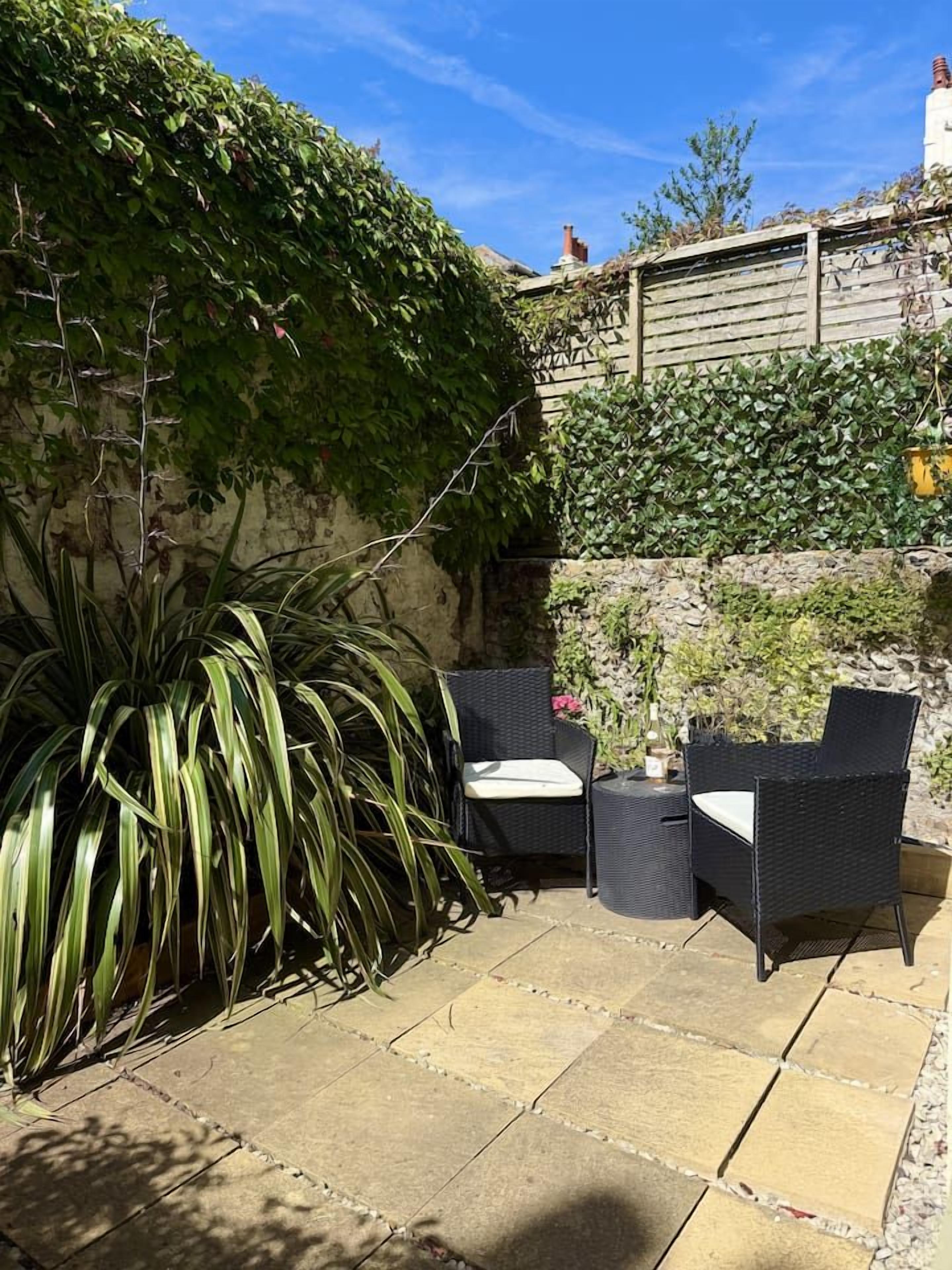 An outdoor patio area with stone flooring, two wicker chairs, and a potted plant.