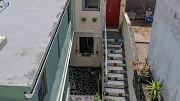 Edifício residencial com porta vermelha, pequena escadaria e vista para o mar.