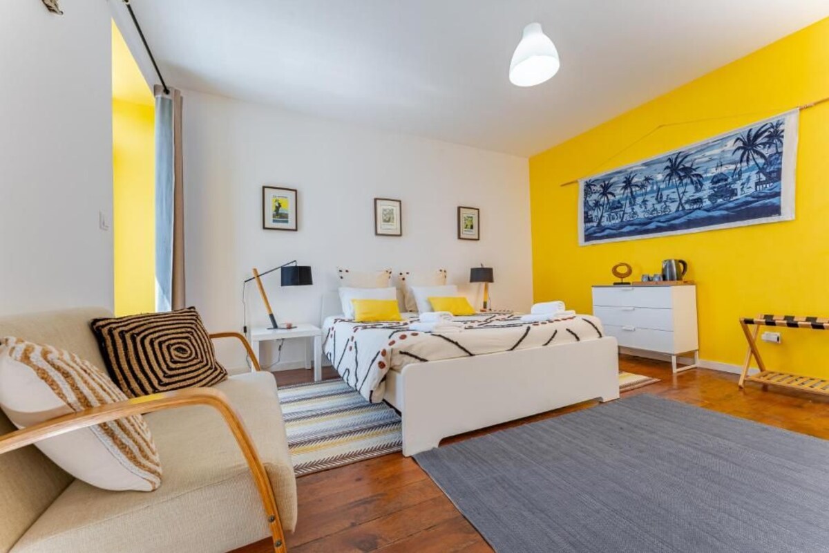 Ett sovrum med en säng, sängbord, en soffa, ett skrivbord och en stol.