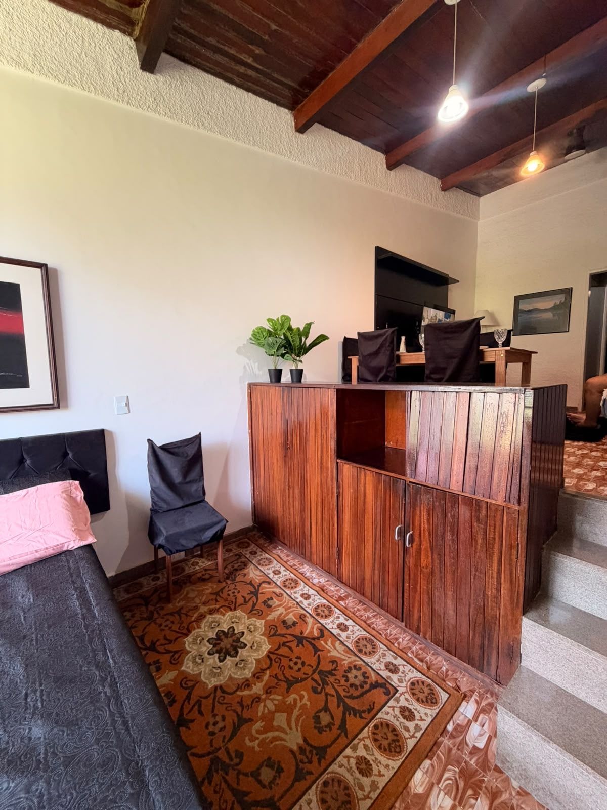 Une pièce comprenant un lit, une armoire en bois, une chaise et un tapis à motifs.