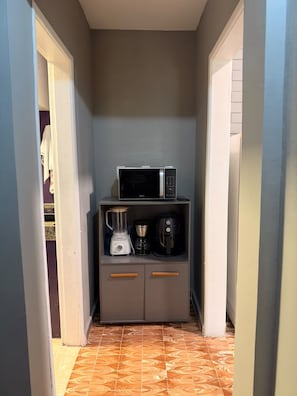 Ein schmaler Flur mit einer Mikrowelle und einer Kaffeemaschine auf einem Schrank.