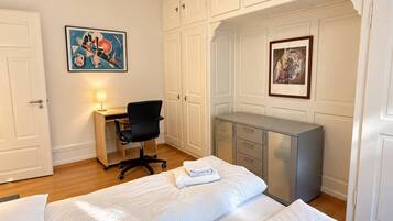 A hotel room with a bed, a desk, a chair, and a wardrobe.