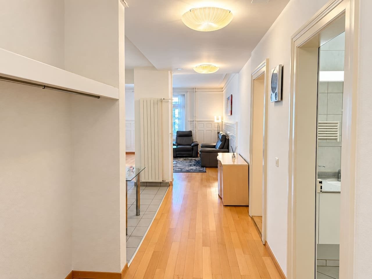 A hallway with a wooden floor leading to a living area with a sofa and a coffee table.