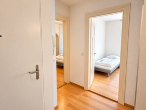 A hallway leading to a bedroom with a bed and a nightstand. - Modern 2-Bedroom Apartment in the City Center - Hösch 10 (Zürich)