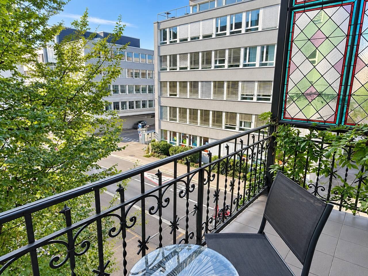 A balcony with a metal railing, a table, and a chair.