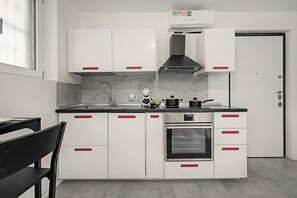 A modern kitchen with white cabinets, a stainless steel oven, and a black range hood. - Apartment 'Smart Hub M3 Metro 10 Min.Duomo' with shared garden, Wi-Fi and air conditioning (Milano)