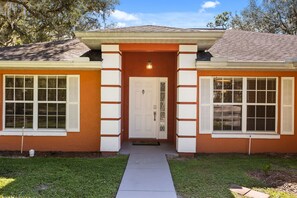 Une maison à deux étages avec un porche à l’avant, une porte dotée d’un panneau en verre et un luminaire placé au-dessus.
