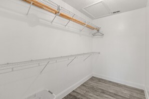 Une pièce aux murs blancs, avec un plancher en bois et deux étendoirs métalliques.